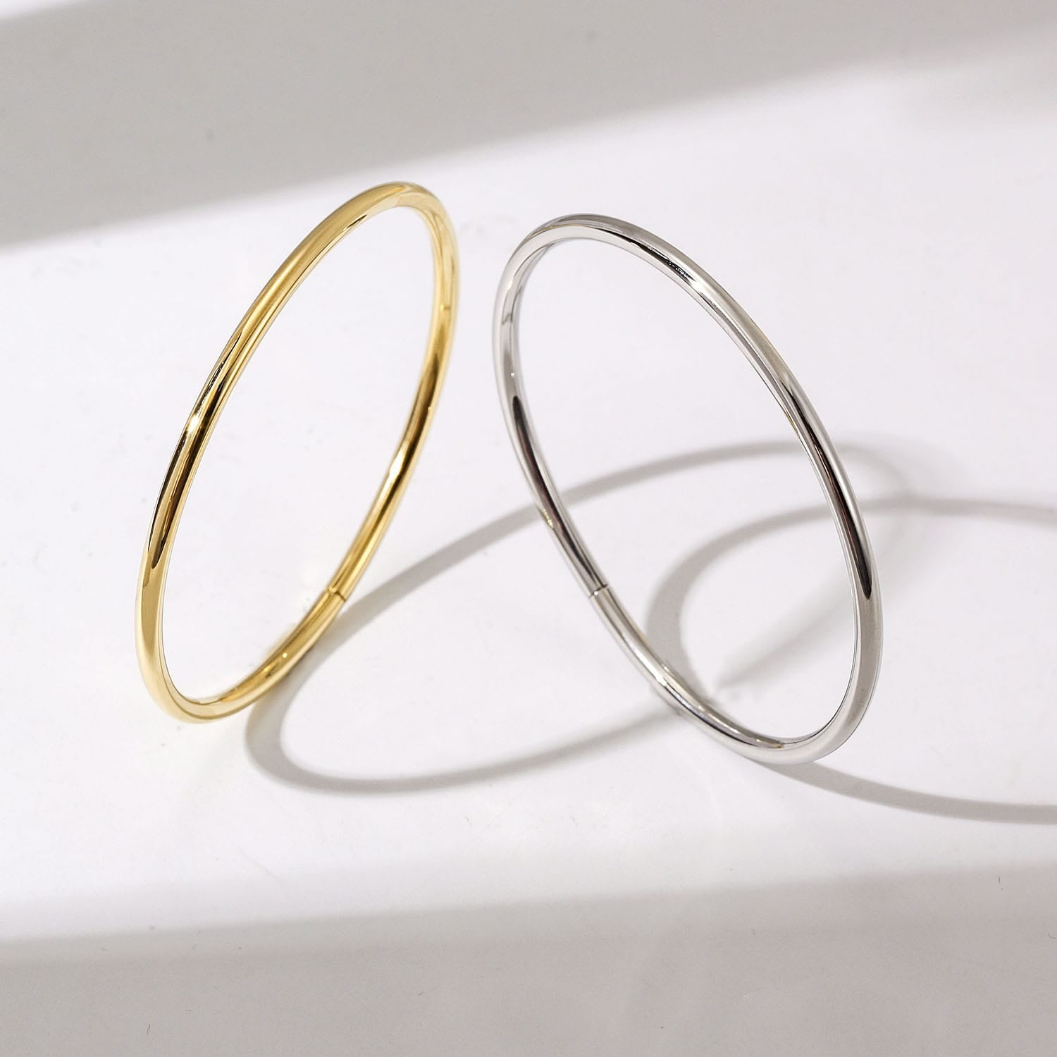 Gold and silver bangles on a light gray background
